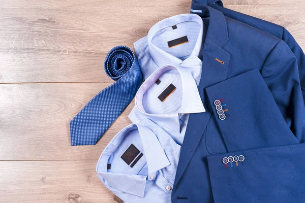 Conjunto de roupas masculinas clássicas - terno azul, camisas, sapatos castanhos, cinto e gravata em fundo de madeira. — Fotografia de Stock