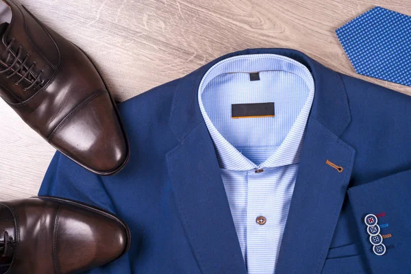 Conjunto de roupas masculinas clássicas - terno azul, camisas, sapatos castanhos, cinto e gravata em fundo de madeira. — Fotografia de Stock