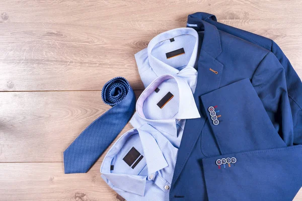 Conjunto de roupas masculinas clássicas - terno azul, camisas, sapatos castanhos, cinto e gravata em fundo de madeira. — Fotografia de Stock