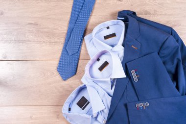 Klasik erkek kıyafetleri - mavi takım, gömlekler, kahverengi ayakkabılar, kemer ve kravat ahşap arka planda.