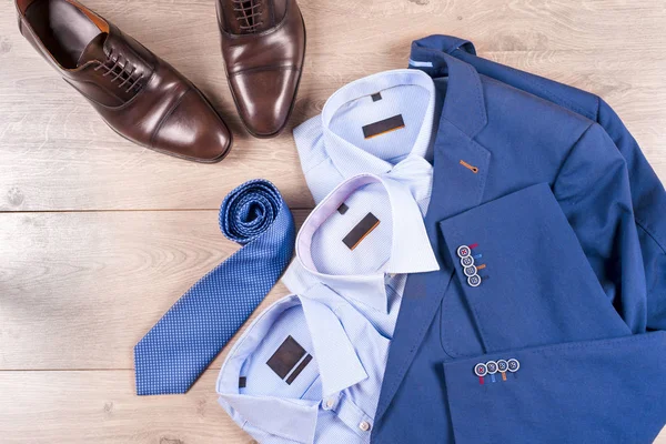 Conjunto de ropa clásica para hombre - traje azul, camisas, zapatos marrones, cinturón y corbata sobre fondo de madera. —  Fotos de Stock