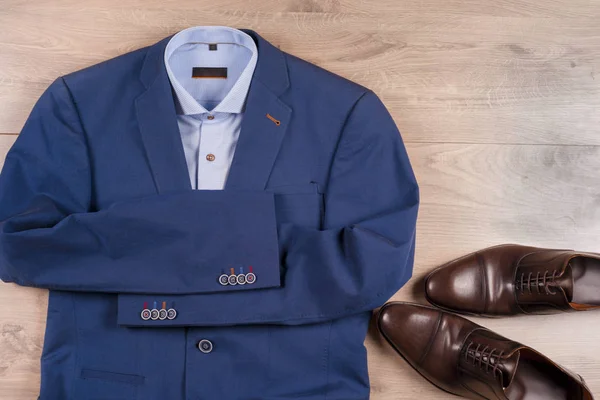 Klasik erkek kıyafetleri - mavi takım, gömlekler, kahverengi ayakkabılar, kemer ve kravat ahşap arka planda.