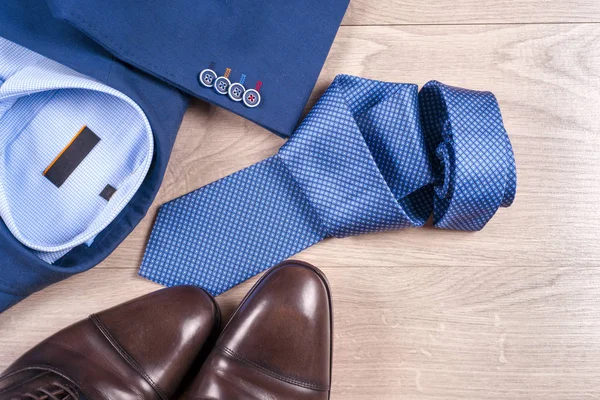 Conjunto de roupas masculinas clássicas - terno azul, camisas, sapatos castanhos, cinto e gravata em fundo de madeira. — Fotografia de Stock