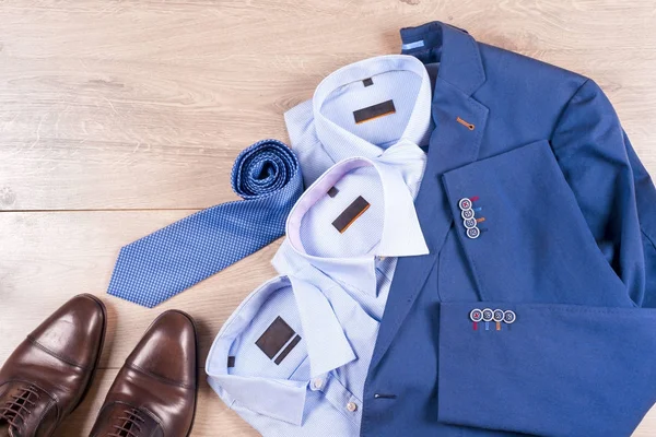 Klasik erkek kıyafetleri - mavi takım, gömlekler, kahverengi ayakkabılar, kemer ve kravat ahşap arka planda.