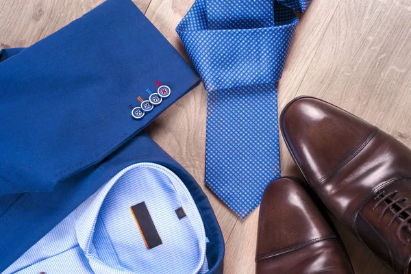 Klasik erkek kıyafetleri - mavi takım, gömlekler, kahverengi ayakkabılar, kemer ve kravat ahşap arka planda.