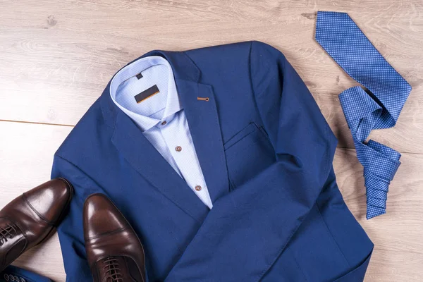 Conjunto de ropa clásica para hombre - traje azul, camisas, zapatos marrones, cinturón y corbata sobre fondo de madera. —  Fotos de Stock