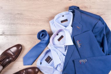 Klasik erkek kıyafetleri - mavi takım, gömlekler, kahverengi ayakkabılar, kemer ve kravat ahşap arka planda.