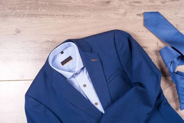 Набір класичного чоловічого одягу - синій костюм, сорочки, коричневе взуття, пояс і краватка на дерев'яному фоні . — стокове фото