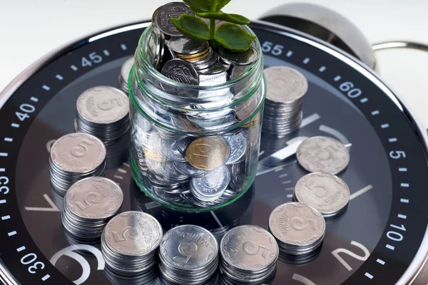 Münzen mit Pflanze und Uhr, isoliert auf weißem Hintergrund. Sparkonzept — Stockfoto