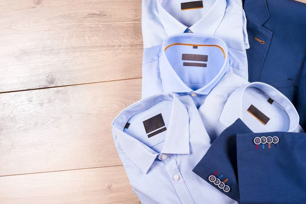Set klassieke herenkleding - blauw pak, shirts, bruine schoenen, riem en stropdas op houten achtergrond. — Stockfoto