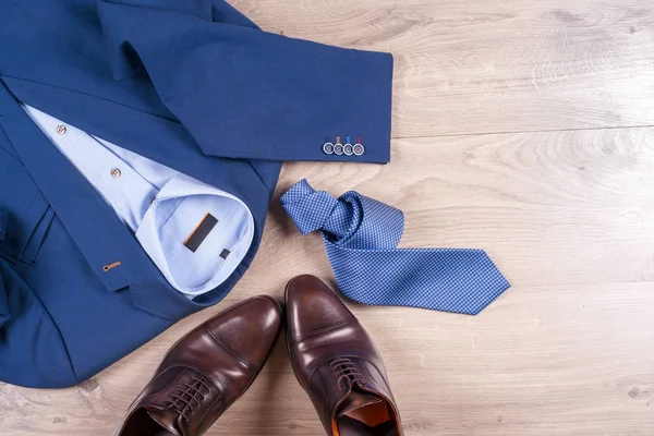 Uppsättning klassiska herrkläder - blå kostym, skjortor, bruna skor, bälte och slips på trä bakgrund. — Stockfoto