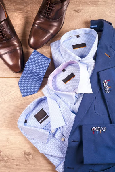 Klasik erkek kıyafetleri - mavi takım, gömlekler, kahverengi ayakkabılar, kemer ve kravat ahşap arka planda. — Stok fotoğraf