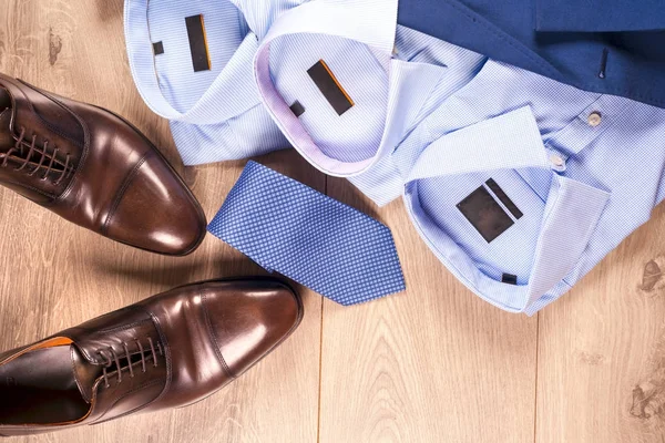 Uppsättning klassiska herrkläder - blå kostym, skjortor, bruna skor, bälte och slips på trä bakgrund. — Stockfoto