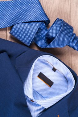 Klasik erkek kıyafetleri - mavi takım, gömlekler, kahverengi ayakkabılar, kemer ve kravat ahşap arka planda.