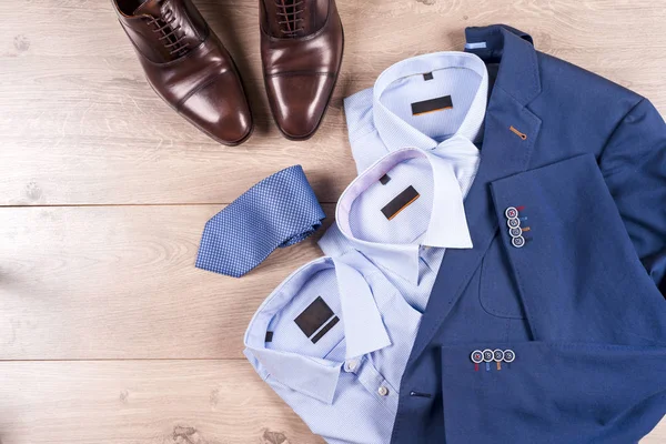 Klasik erkek kıyafetleri - mavi takım, gömlekler, kahverengi ayakkabılar, kemer ve kravat ahşap arka planda.