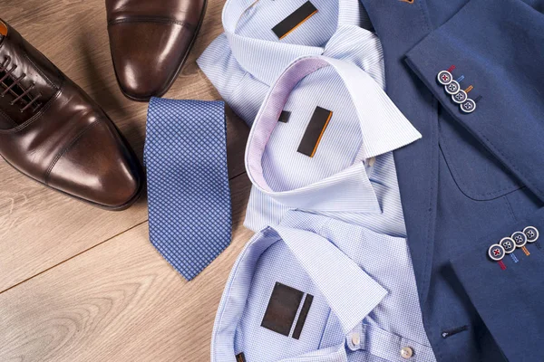 Conjunto de roupas masculinas clássicas - terno azul, camisas, sapatos castanhos, cinto e gravata em fundo de madeira. — Fotografia de Stock