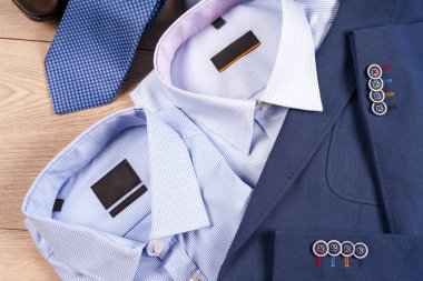 Klasik erkek kıyafetleri - mavi takım, gömlekler, kahverengi ayakkabılar, kemer ve kravat ahşap arka planda.