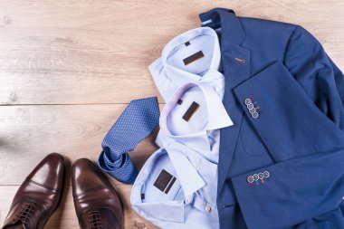 Klasik erkek kıyafetleri - mavi takım, gömlekler, kahverengi ayakkabılar, kemer ve kravat ahşap arka planda.