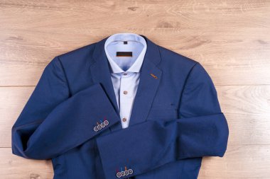 Klasik erkek kıyafetleri - mavi takım, gömlekler, kahverengi ayakkabılar, kemer ve kravat ahşap arka planda.