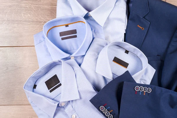 Klasik erkek kıyafetleri - mavi takım, gömlekler, kahverengi ayakkabılar, kemer ve kravat ahşap arka planda.