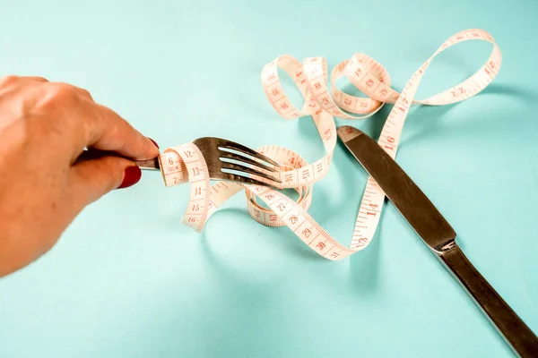 Tenedor y cuchillo con un centímetro sobre un fondo azul, dieta, estilo de vida saludable . — Foto de Stock