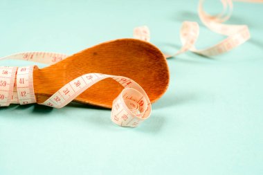 Tahta kaşıkla bir ölçüm bandı bir mavi arka plan, diyet, sağlıklı yaşam tarzı.