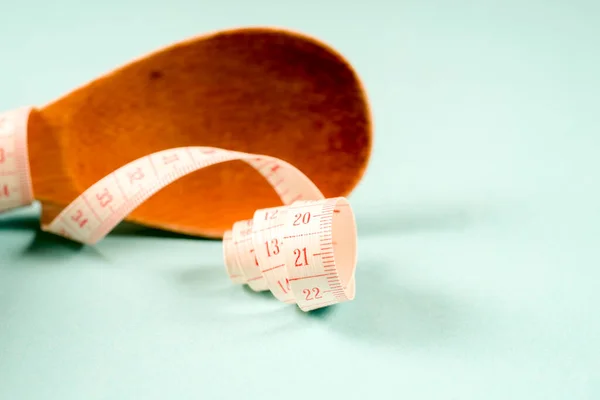 Cuchara de madera con cinta métrica sobre fondo azul, dieta, estilo de vida saludable . — Foto de Stock