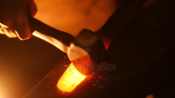 Un forgeron forge une épée avec un marteau sur une enclume au ralenti 