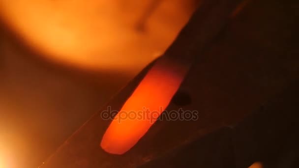 Un forgeron frappant barre de métal chaud avec un marteau sur une enclume 