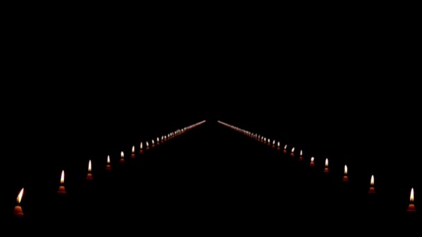 Двигаясь по длинному пути свечей в темноте — стоковое видео