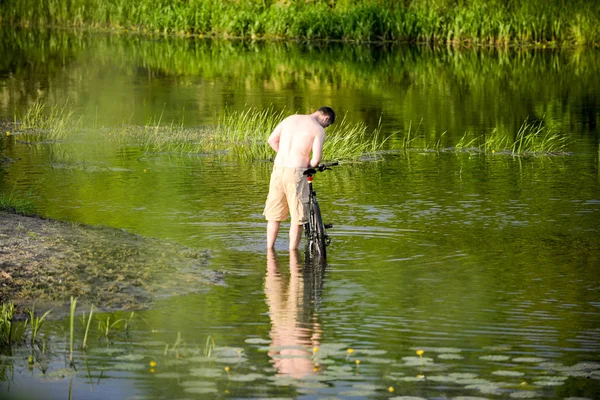 De man wast de fiets in de rivier Snov — Stockfoto
