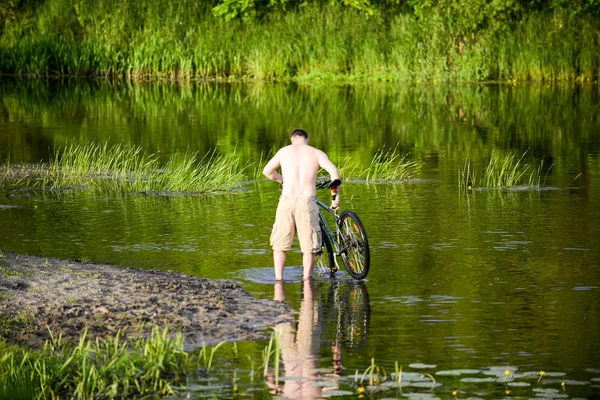 Adam nehre Snov Bisiklet yıkar