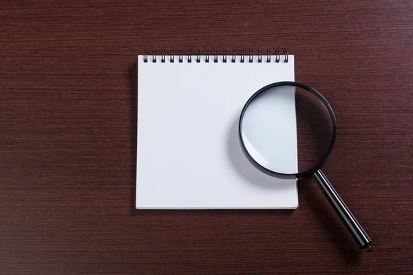 Notebook and magnifying glass