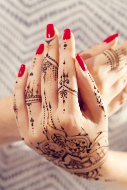 Kırmızı manikürlü eller Mehndi ile 