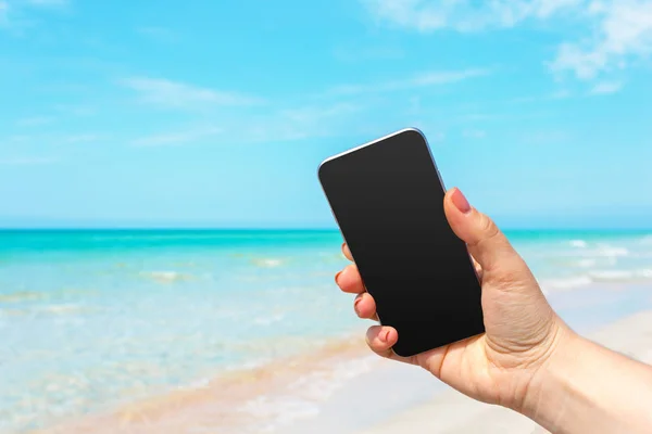 美丽的女人的手在海滩使用智能手机 — 图库照片