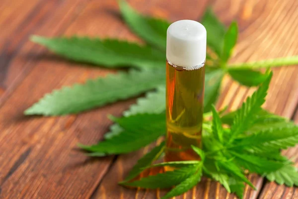 Cannabis leaves and oil on wooden background