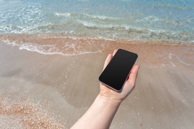 Kumsalda Smartphone kullanarak güzel kadın eli