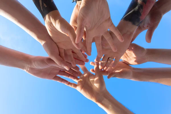 friends stacking hands on sky background