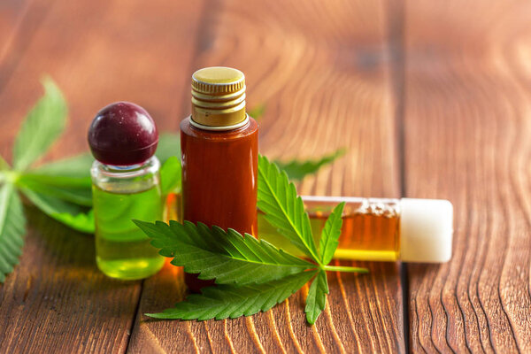 Cannabis leaves and oil on wooden background