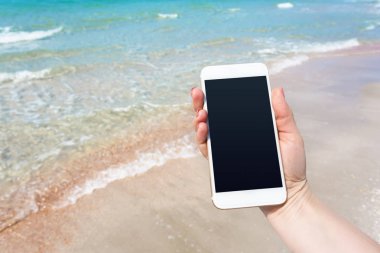 Kumsalda Smartphone kullanarak güzel kadın eli