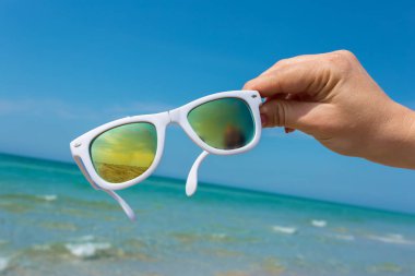 Plaj arka plan üzerinde elinde güneş gözlüğü