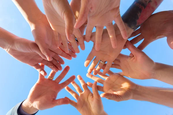 friends stacking hands on sky background