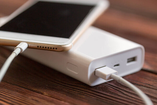 банк питания и сотовый телефон на деревянном столе, современные гаджеты фон
 