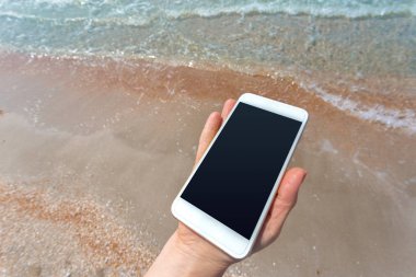 Kumsalda Smartphone kullanarak güzel kadın eli