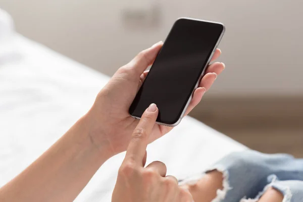 Woman checking the cellphone on the bed