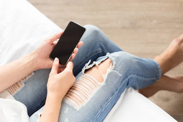 Woman checking the cellphone on the bed