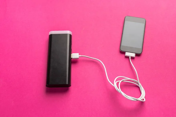 Smartphone charging with power bank on table background