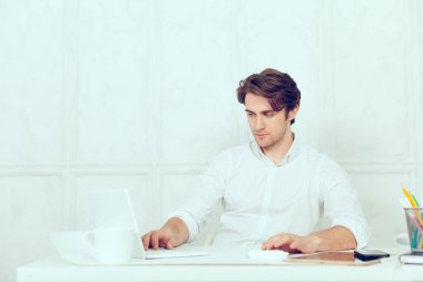Laptop ve kalem kullanarak tablo oturan işadamı