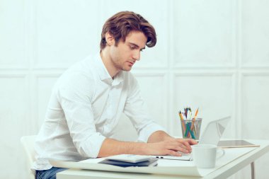 Laptop ve kalem kullanarak tablo oturan işadamı