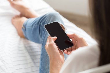 Kadın yatakta cep telefonu kontrol